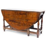 An 18thC oak drop leaf table, with an oval top on turned legs with stretchers, 74.5cm high, 137cm