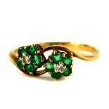 A 9ct gold dress ring, set with two flower designs, each with emerald and tiny diamond, on twist