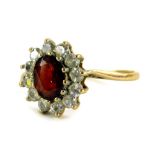 A 9ct gold floral cluster ring, the central garnet surrounded by various CZ stones, in a claw