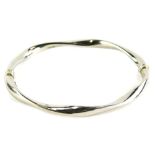 A 9ct white gold hinged bangle, of wave design with magnetic clasp, and safety attachment, stamped