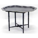 A black painted toleware tray table, with a shaped gilt border, turned simulated bamboo base, X
