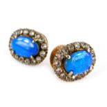 A pair of opal and paste stone earrings, the oval central stone surrounded by white stones in claw