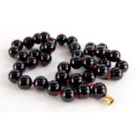 A garnet necklace, with various spherical beads, each approx 1cm wide, on a red knotted string, with