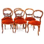 A set of six Victorian rosewood balloon back dining chairs, each with a carved crest, a padded seat,