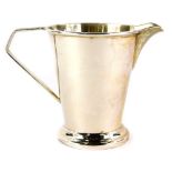 A George VI silver cream jug, the plain body with a plain spout and angular ear handle, engraved
