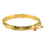 An early 20thC 9ct gold bangle, with rectangular etched design sections, on a single clasp, with