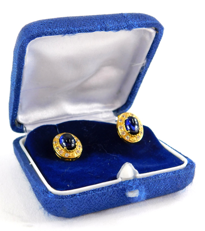 A pair of sapphire and diamond earrings, each with central cabochon cut sapphire in four claw