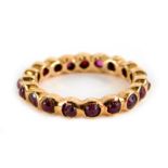 A garnet eternity ring, set with various cabochon cut stones, in a rose gold coloured setting,