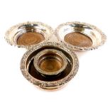 Four silver plated wine coaters, each with turned wooden bases, the largest 19cm diameter.