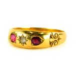 An Edwardian 18ct gold dress ring, set with central star set diamond and two rubies, with scroll