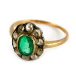 An emerald and diamond dress ring, in floral cluster with central oval cut emerald, surrounded by