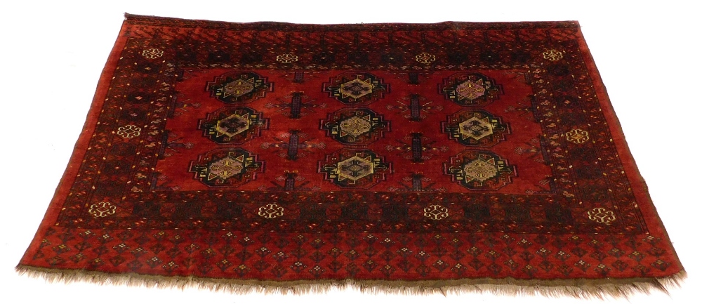 A Turkoman type rug, with a design of nine medallions on a red ground with multiple borders, 175cm x