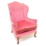 An early 20thC mahogany wing back armchair in George III style, upholstered in pink fabric, on