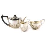An associated silver three piece tea set, with part fluted decoration, the teapot with an ebonised