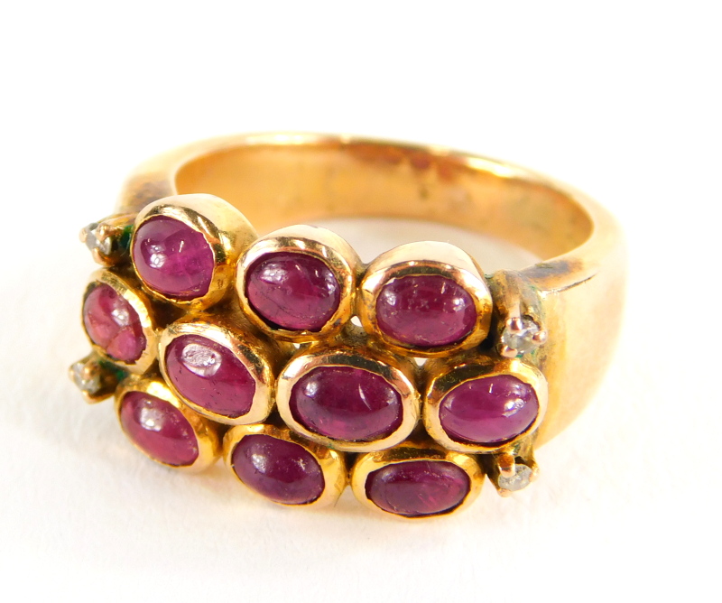 A ruby and diamond dress ring, with three rows of cabochon cut rubies and four tiny diamonds, on a
