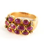 A ruby and diamond dress ring, with three rows of cabochon cut rubies and four tiny diamonds, on a