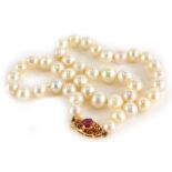 A natural pearl necklace, the oval clasp set with garnet in four claw setting, yellow metal,