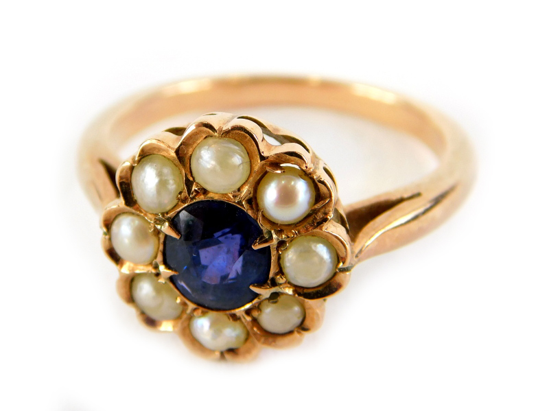 A sapphire and seed pearl daisy ring, the central oval cut sapphire surrounded by seed pearls, in