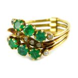 An emerald and diamond tri-band ring, the two outer bands set with design on three emeralds and four