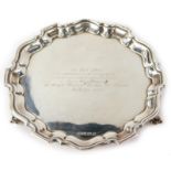 An Elizabeth II silver salver, with piecrust border on shell supports, with the inscription to