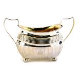 A William IV two handled silver sugar bowl, with part reeded decoration and engraved monogram, on