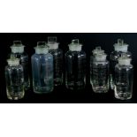 A collection of chemists bottles, each with black lettering and stopper, the largest 20cm high.