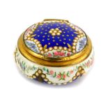 A continental enamel circular pill box, decorated with flowers, stars, stylised pearls picked out in