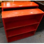 Two red painted open bookcases.
