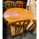 A circular teak extending dining table and four chairs.