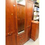 A modern wardrobe with central mirror and drawers, and a matching chest of drawers.