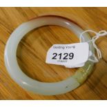 A modern jade bangle, of pale green and orange colour, (AF), 47.2g all in.