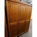 A pine triple wardrobe with panelled doors and bun feet, 183cm high, 140cm wide.