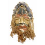 A heavily carved African tribal head, with hair and beard picked out with shells, with pierced eyes,