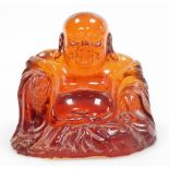 An amber coloured resin figure of Buddha, in seated pose wearing flowing robes, 13cm high.