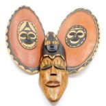 Tribal Art. A painted and carved timber wall mask, and two painted and timber shields, the wall mask
