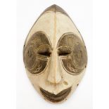 An African tribal face mask, of shaped ellipse form with pierced eyes, partially carved face and