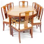 A late 20thC Eastern hardwood extending dining table and eight chairs, the circular dining table