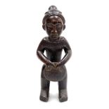 An African tribal carved figure, formed holding drum, with elaborate head dress, 34cm high.