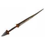 An African tribal knife, with tapering blade, turned handle with metal arrowhead pommel, 68cm wide.