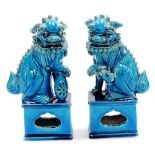 A pair of Chinese turquoise glazed pottery dogs of fo, each on shaped partially pierced bases,