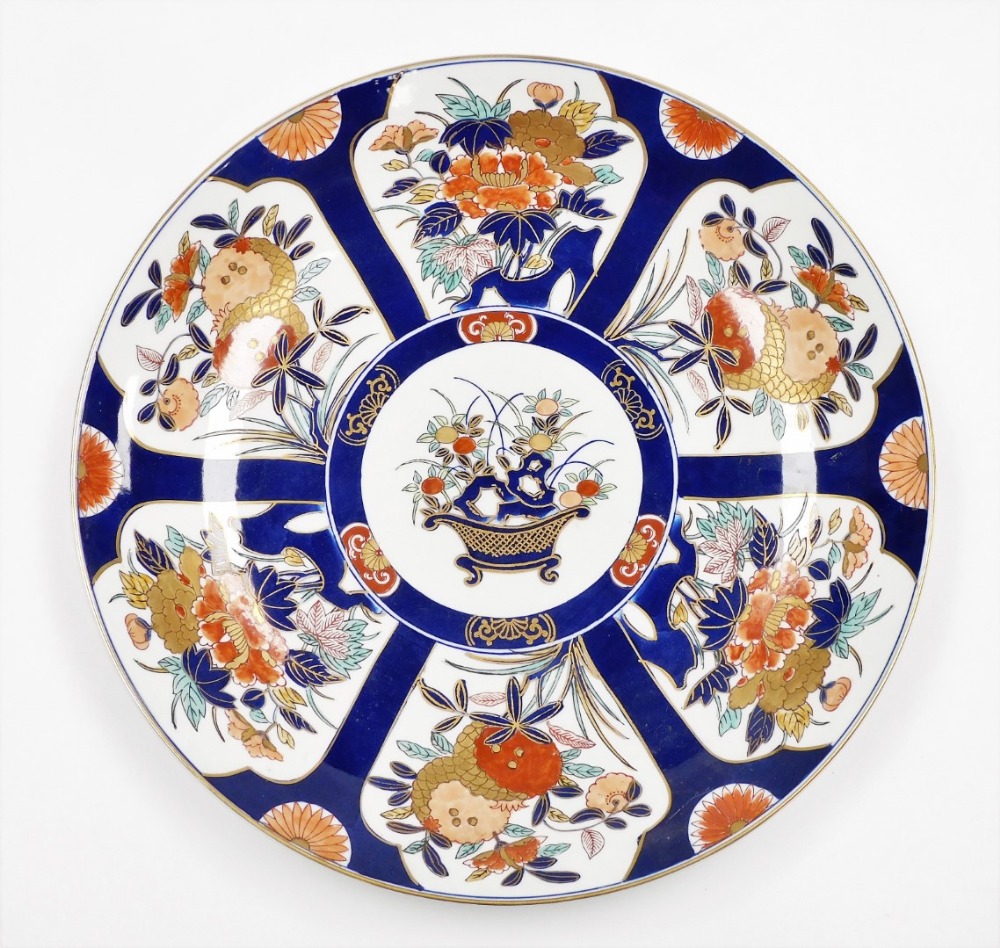 A Japanese Imari charger with basket of flowers, surrounded by panels of floral bouquets on a blue