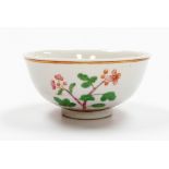 A Chinese porcelain bowl decorated in green and pink enamels, with flowering branches above a