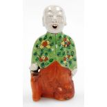 A Chinese spill holder modelled as a kneeling child with smiling expression, glazed predominantly in