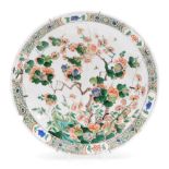 A Chinese Kangxi porcelain dish, profusely decorated with flowering shrubs, predominantly in orange,