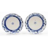 A pair of Japanese porcelain blue and white plates, with central floral emblems and outer panels