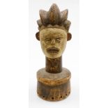 An African tribal hardwood head figure, with elongated features, shell eyes and open mouth, on a