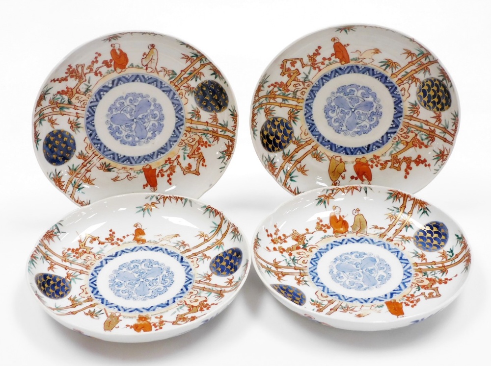 A set of four Japanese Imari porcelain plates, decorated with figures among bamboo and prunus,