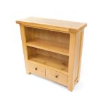 A light oak open bookcase, of two shelves over a pair of frieze drawers, raised on block feet,