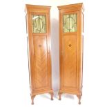 A pair of Edwardian mahogany and inlaid wardrobe sections, each with an outswept pediment over a