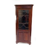 An Edwardian mahogany corner cabinet, the dentil moulded pediment over a glazed door opening to